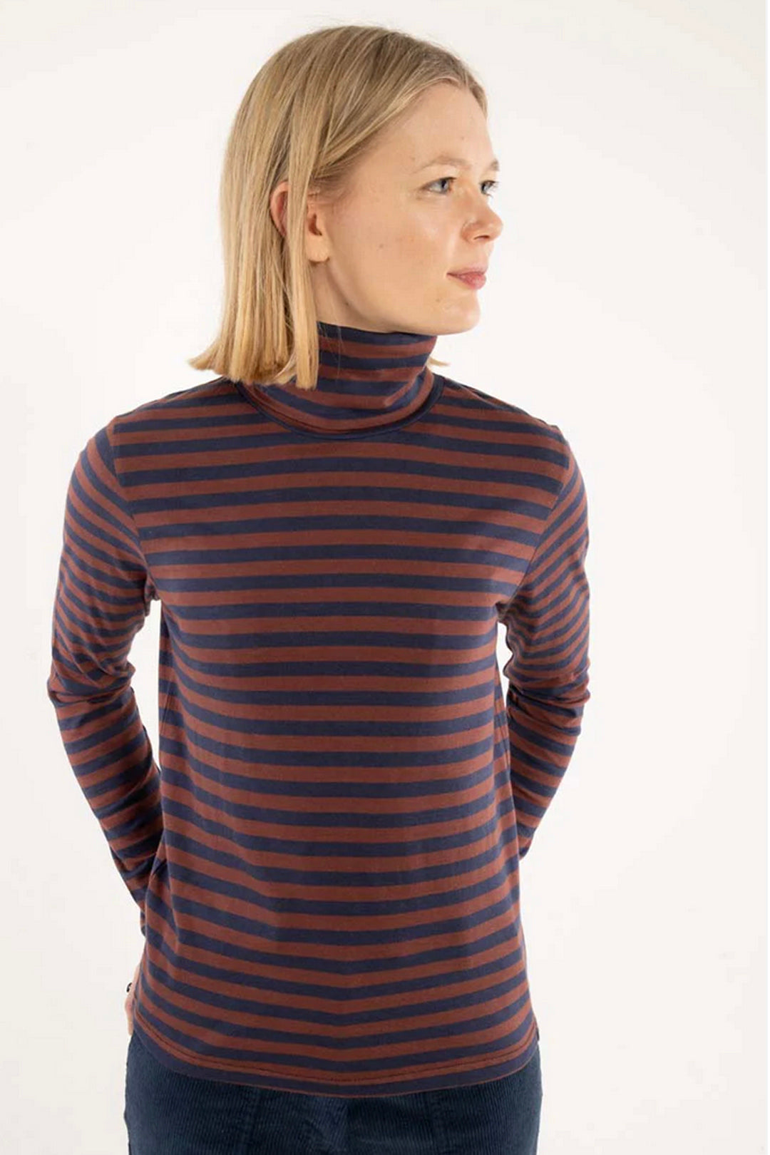 Woman wearing a striped long-sleeve turtleneck against a white background