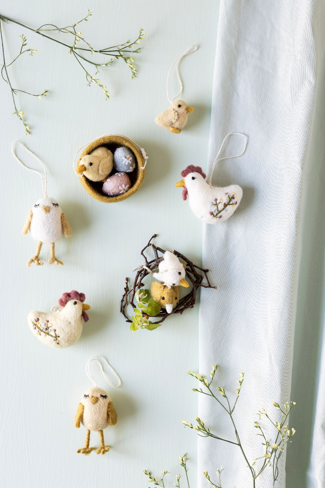 Decorative Easter ornaments including chickens and a nest with eggs on a light background.