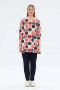Woman wearing a patterned long-sleeve top and dark pants on a white background
