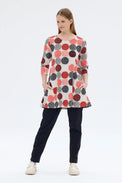 Woman wearing a patterned dress with red and black dots on a white background