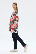 Woman wearing a colorful polka dot dress with black pants on a white background