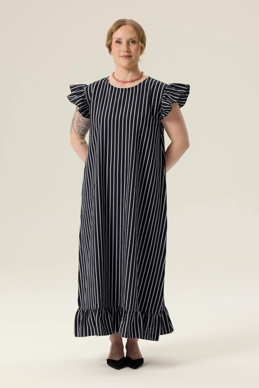 Woman wearing a black and white striped dress on a plain background