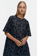 Woman wearing a blue dress with white floral pattern on a plain background