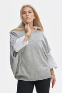 Woman wearing a gray poncho over a white shirt on a white background
