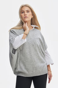 Woman wearing a gray poncho over a white shirt on a white background