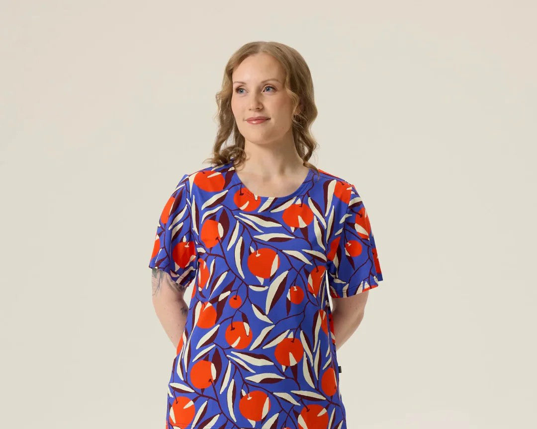 Woman wearing a blue dress with red and white fruit pattern on a beige background