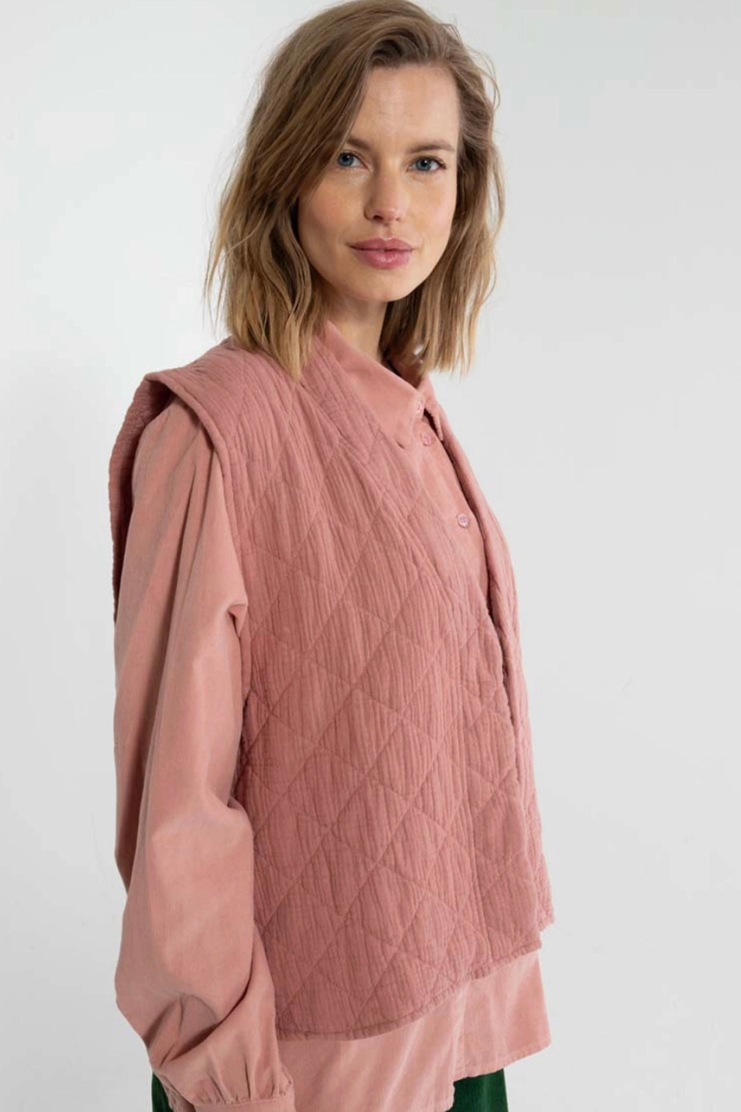 Woman wearing a pink quilted west on a white background