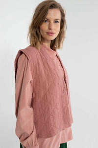 Woman wearing a pink quilted west on a white background